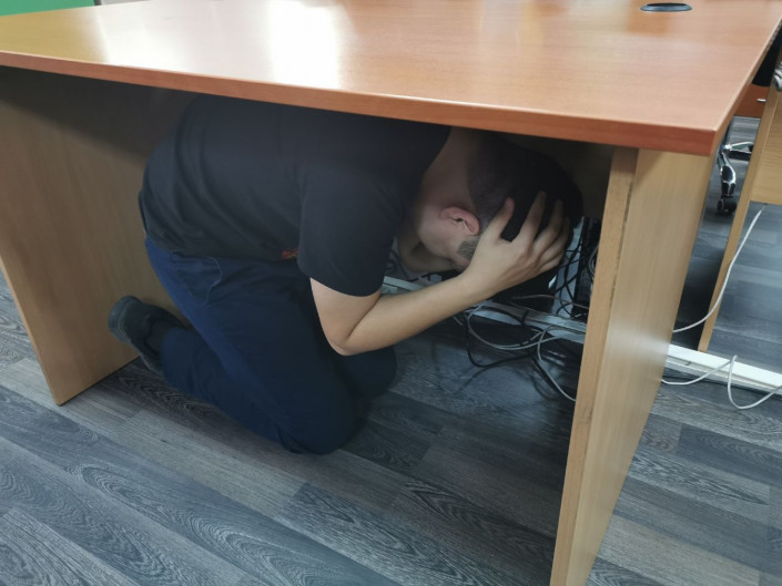 Стол подглядывание. Человек под столом. Спрятался под столом. Человек прячется под столом. Под столом в школе.